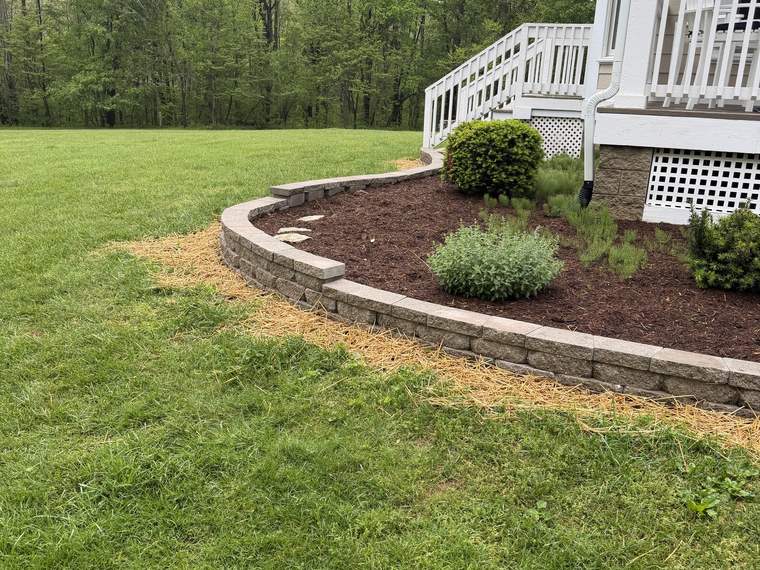 Curved segmental block wall retaining a mulched bed beside a house