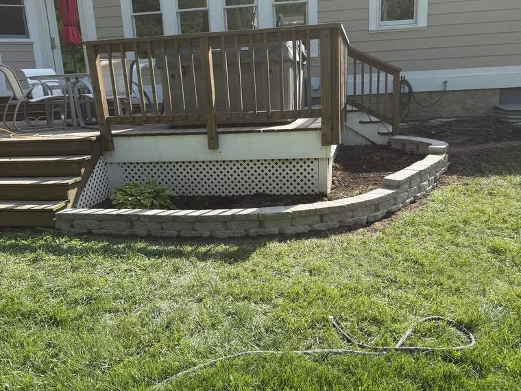 Block retaining wall built around deck steps and a patio landing