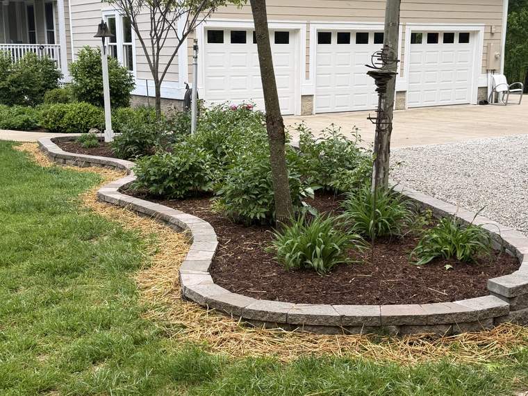 Block retaining wall curving around a bed at the edge of a driveway
