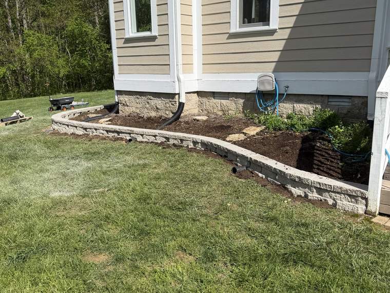 Block retaining wall running along the side of a house to hold grade