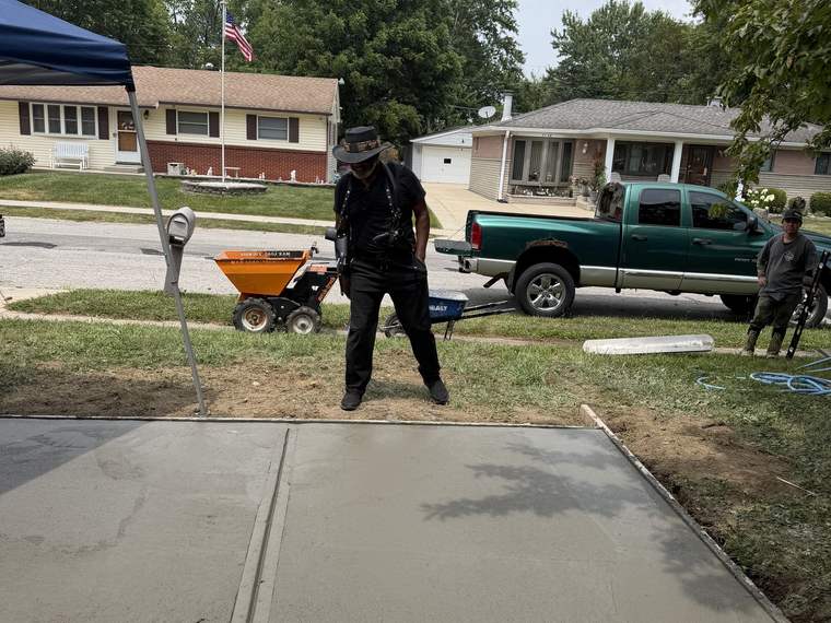 Crew finishing a freshly poured concrete pad in a front yard