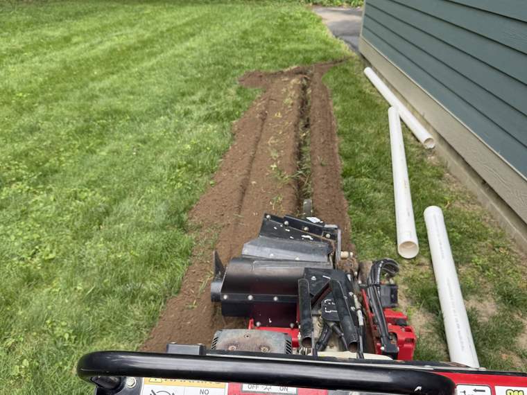 Directional boring machine running a new line beside a house without open trenching