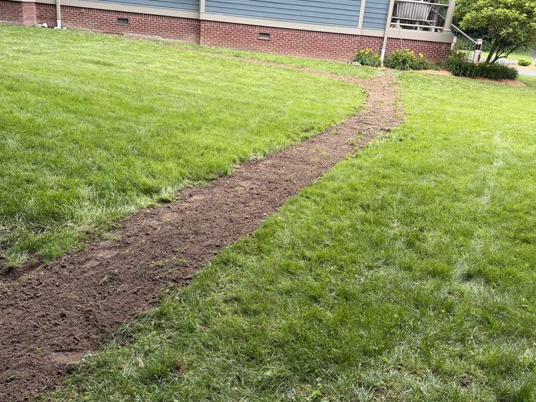 Fresh drainage run crossing a front lawn toward the street