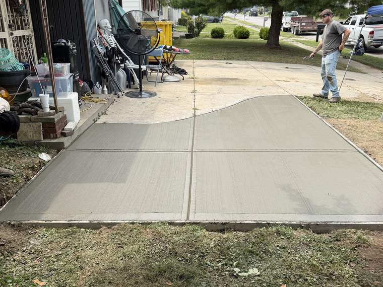 Finished concrete driveway apron poured up to a garage