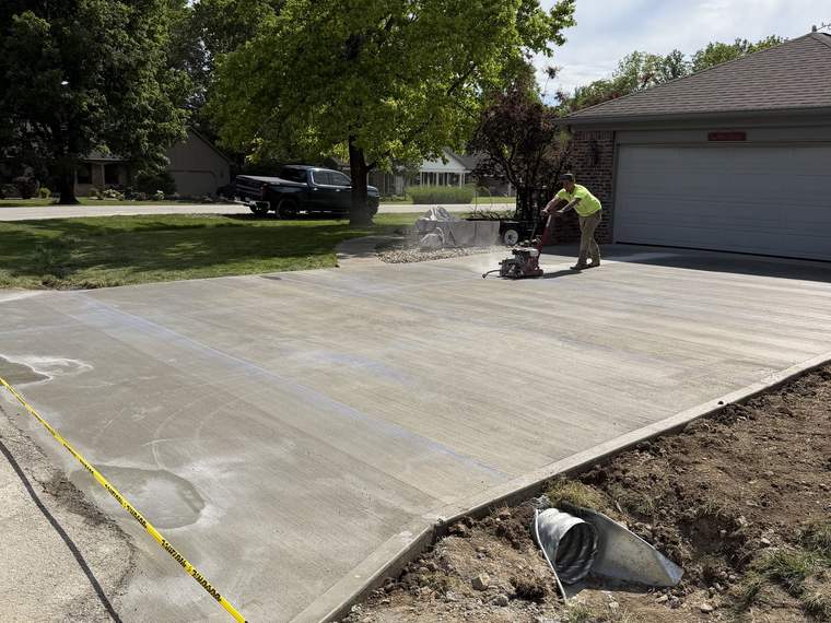 Concrete driveway being finished with a power trowel by the crew