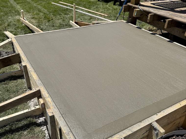 Concrete pad poured inside timber forms in a back yard