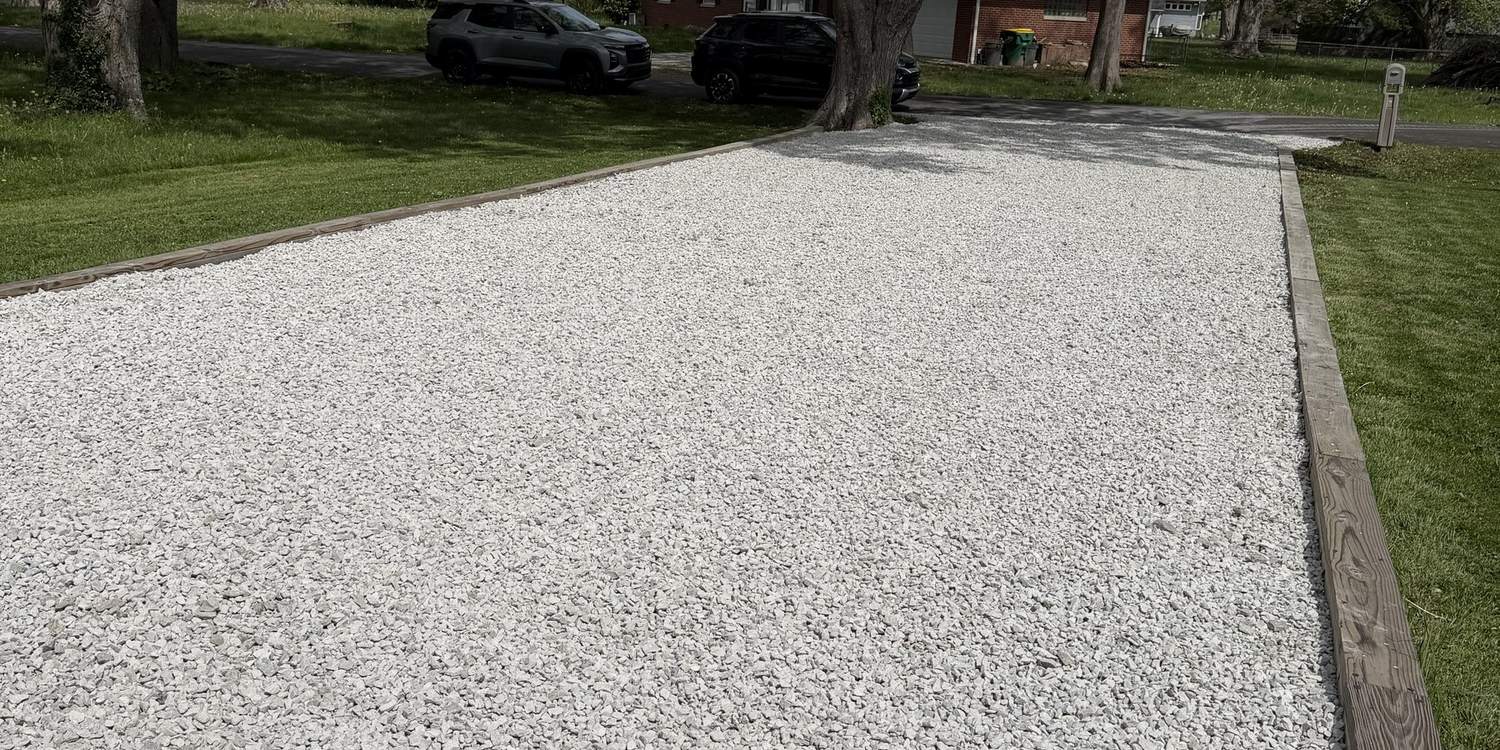 New crushed stone driveway installed between mature trees