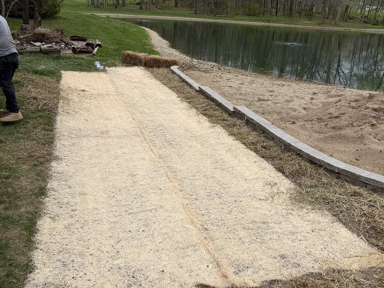 Graded sand beach approach shaped down to the edge of a pond