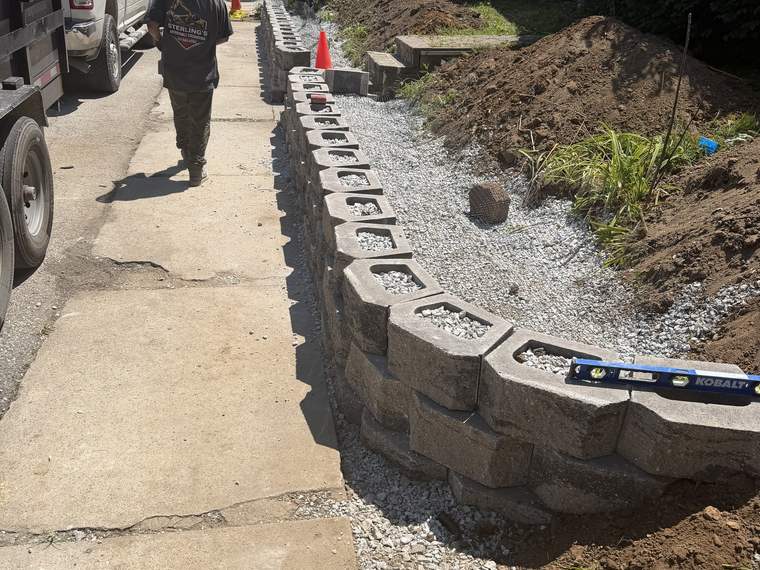 Retaining wall block being set and leveled course by course