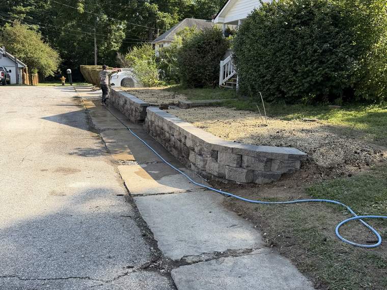 Finished block retaining wall holding the grade beside a concrete driveway