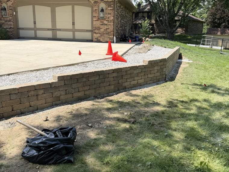 Block retaining wall built to support the edge of a gravel driveway