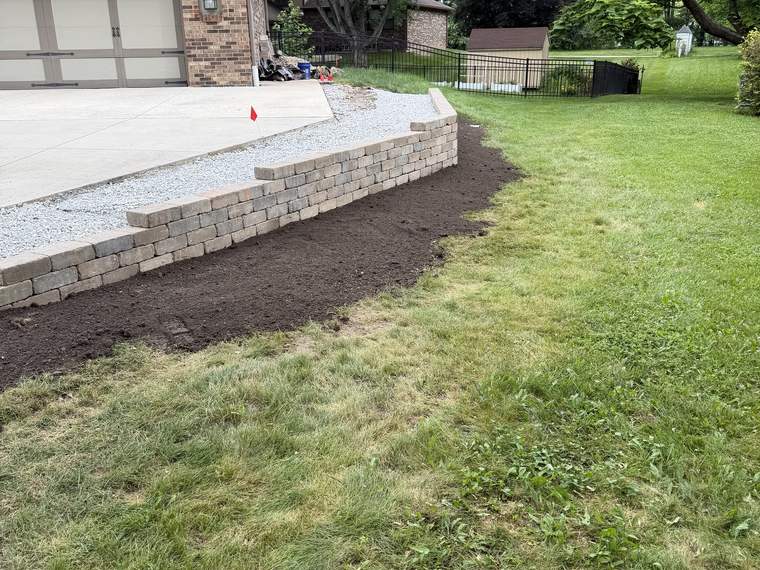 Finished block retaining wall with fresh mulch and restored lawn