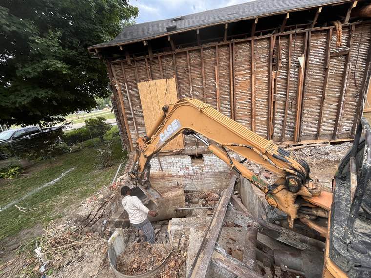 Excavator taking a structure down to its framing and foundation
