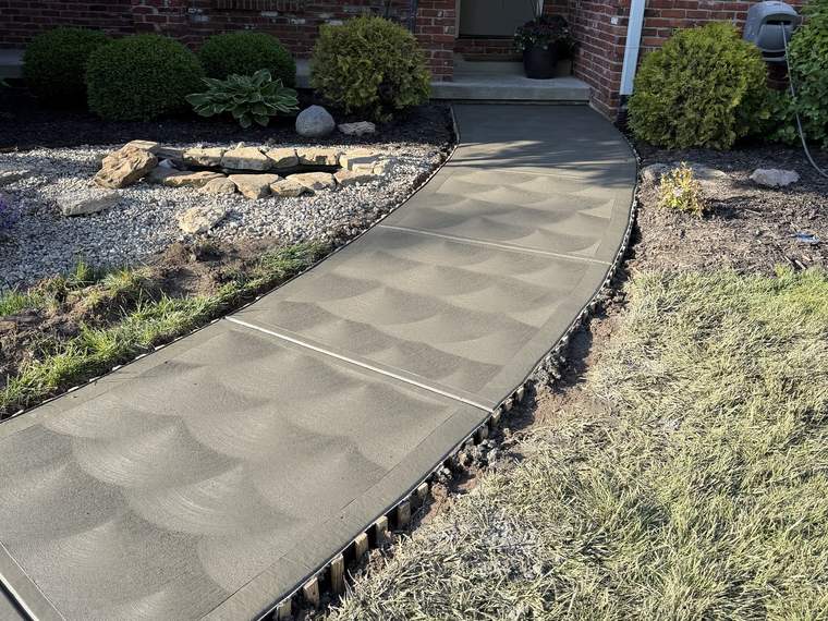Curved concrete walkway with a swirl finish leading to a front entry